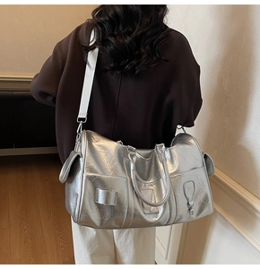 Détail du sac de voyage argenté avec bandoulière réglable et surface texturée