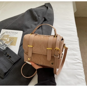 Détail du sac à main beige en cuir texturé avec garniture dorée et lanières nouées