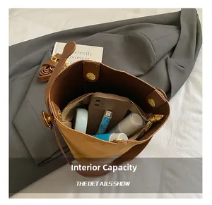 Internal capacity of the brown nubuck bucket bag showing daily items and magnetic clasp
