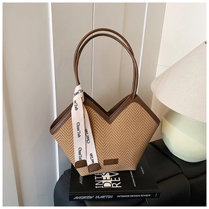 Detail of herringbone straw tote bag with brown leather trim and printed silk scarf