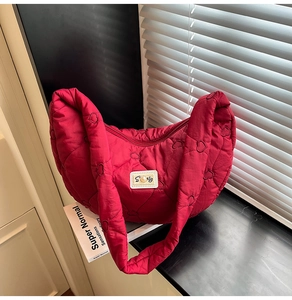 Detail of red quilted heart pattern puffer bag with pearl S patch and secure zipper