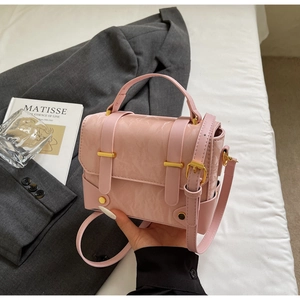 Détail du sac à main rose clair avec texture pierre et boucles métalliques dorées