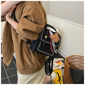 Detail of vintage black crossbody bag featuring contrast stitching and cute bear charm