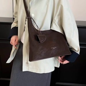 Detail view of deep brown matte leather underarm bag with MUFANNI logo on the side