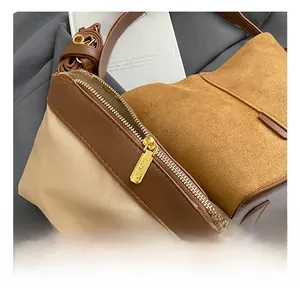 Close-up of golden metal zipper puller with engraved logo on brown suede bucket bag