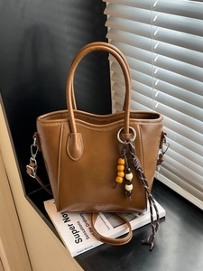 Sac seau minimaliste en cuir marron avec breloque en bois et jeu d'ombres élégant