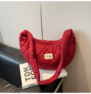 Detail of red quilted heart pattern shoulder bag with pearl patch on a half-moon shape