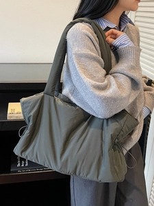 Olive green large capacity quilted nylon shoulder tote bag worn by a female model