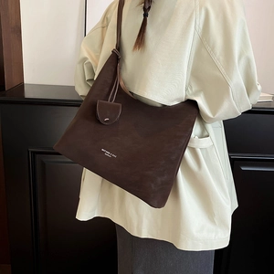 Detail view of large dark brown hobo shoulder bag with matte leather texture and charm
