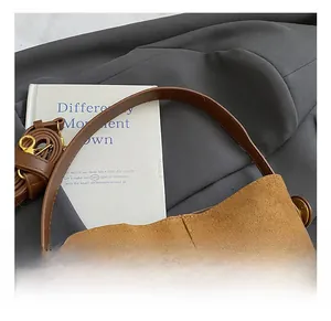 Close-up of brown matte suede handbag with smooth leather straps and gold metal buckle