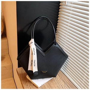 Detail of black quilted tote bag with V-shaped opening and decorative silk scarf on handle