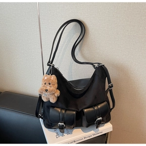 Detail view of black tote bag featuring two cargo pockets and a cute plush bear pendant
