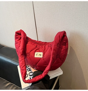 Detail of red heart-quilted puffer bag with pearl logo and thick shoulder strap