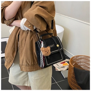 Detail of vintage black leather mini backpack with bear charm and striped silk scarf
