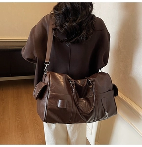 Détail d'un grand sac de voyage en cuir marron avec texture, poignée et poche latérale