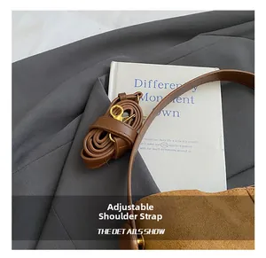 Detail of adjustable brown leather shoulder strap on a matte texture bucket bag