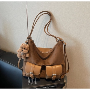 Detail of faux suede tote bag featuring front buckle pockets and brown plush bear charm