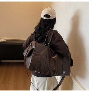 Détail d'un grand sac de voyage marron avec poches latérales et bandoulière longue