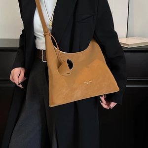 Detail of tan leather tote bag with round charm and brand logo for office style