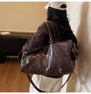 Détail du sac de voyage en similicuir marron foncé avec texture rétro et bandoulière