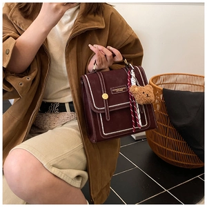 Detail view of deep red vintage backpack featuring pearl trim and elegant gold buckle