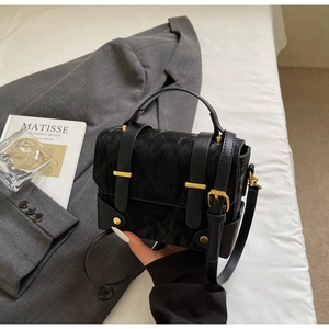 Gros plan d'un sac à main noir texturé avec boucle dorée et décor artistique chic