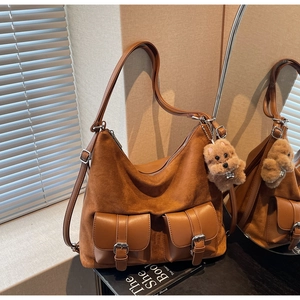 Close-up of brown suede tote bag featuring front buckle pockets and a cute teddy charm