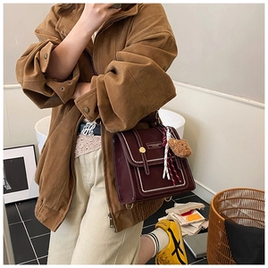 Detail view of burgundy leather vintage crossbody bag with white stitching and bear charm