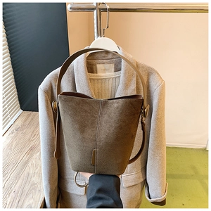 Detailed view of brown frosted suede bucket bag with fine stitching and brass metal hardware