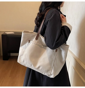 Detail of canvas tote bag with leather strap and metal rivet reinforcement for commute