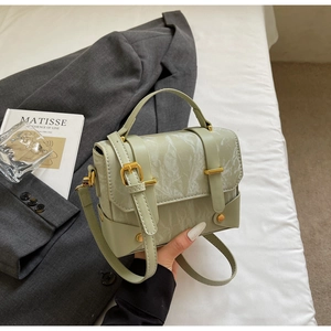 Détail de la texture cuir vert marbre avec fermoir doré sur ce sac à main élégant
