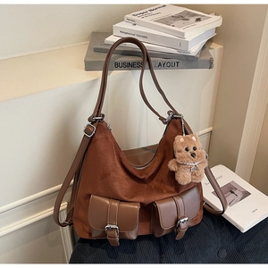 Detail of suede and leather tote bag featuring two front pockets with metal buckles