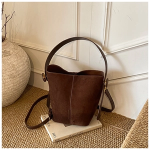 Detail view of dark brown frosted suede bucket bag with vintage gold metal hardware