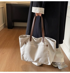 Detail of canvas tote bag with brown leather handles and metal rivet reinforcement