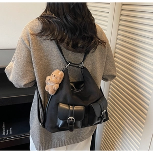 Detail of black commuter backpack with utility buckle pockets and cute plush bear charm