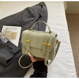 Détail d'un petit sac à main vert clair marbré avec ferrures dorées et poignée haute