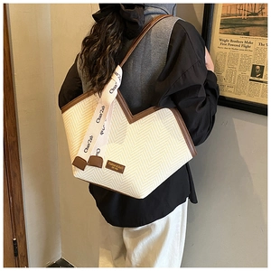 Detailed view of chevron woven tote bag with contrast brown trim and v-shaped opening
