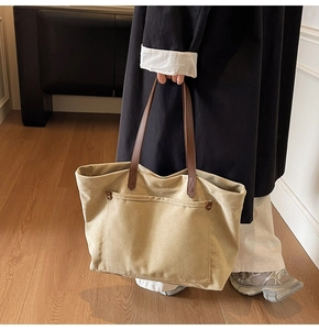 Detail of khaki canvas tote bag with brown leather straps and large external pocket