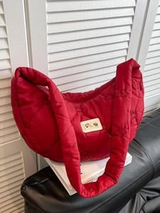 Quilted red heart pattern hobo bag with pearl patch on a stylish leather sofa