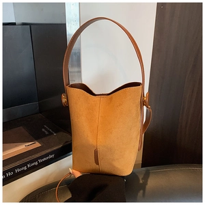 Detail of camel suede bucket bag with brown leather strap and metal buckle
