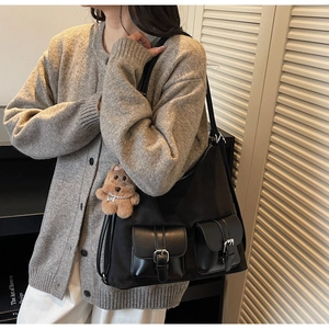 Detail of black tote bag with leather strap pockets and a cute plush bear pendant