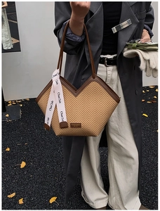 Close-up of woven straw tote bag with brown leather trim and V-shaped opening details