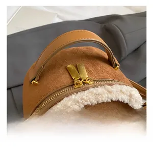 Detail der braunen Wildlederstruktur mit weißem Teddyfutter und goldenen Reißverschlüssen