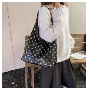 Detail of black leather hobo bag with silver studs styled with a knit sweater