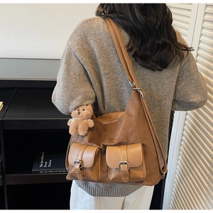 Detail view of brown suede patchwork tote bag with front pockets and cute bear charm