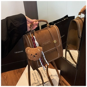 Detail of vintage brown shoulder bag with contrast stitching and bear charm