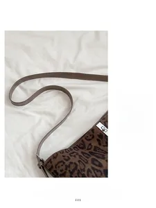 Close-up of leopard print bucket bag with silver metal buckle on white fabric