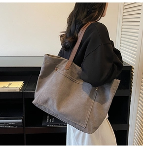 Detail view of large canvas tote bag with brown leather straps and white contrast stitching