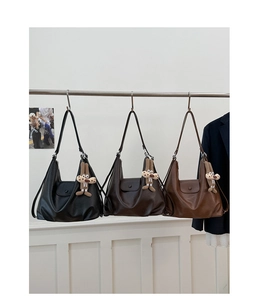 Detailed view of three minimalist leather tote bags in black, coffee, and brown with charms