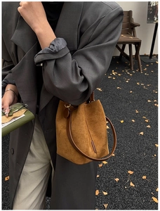 Close-up of brown frosted leather bucket bag featuring slim straps in autumn outdoor setting